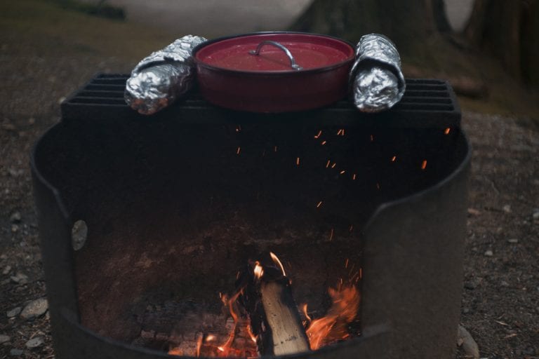 Image of garlic bread wrapped in tinfoil and spaghetti sauce being warmed over a campfire at Golden Ears Provincial Park