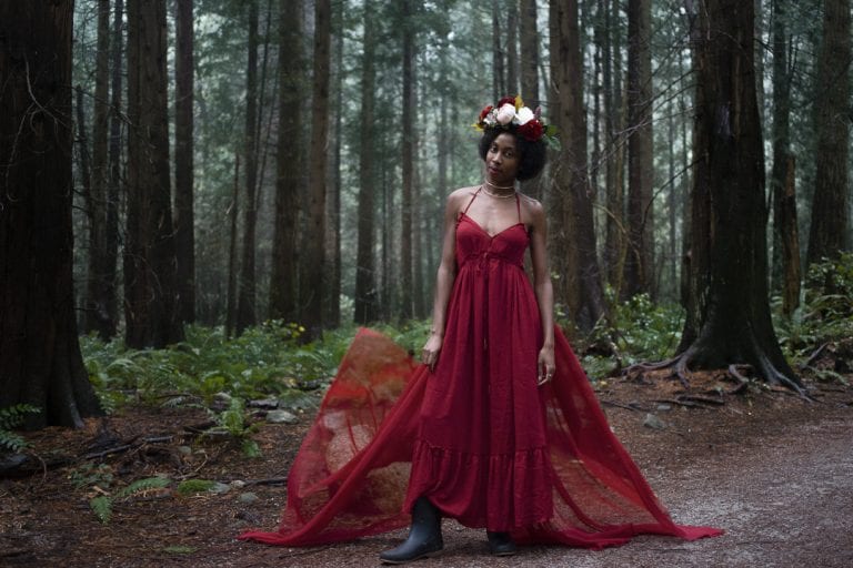 Outdoor portraits at Pacific Spirit National Park in natural light of a young woman in a red dress and flower crown standing in the forest by Vancouver contemporary portrait photographer Angela McConnell
