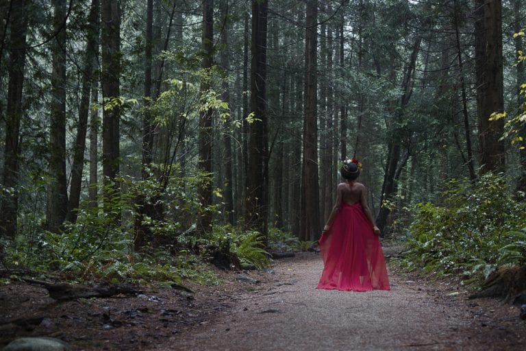 Outdoor portraits at Pacific Spirit National Park in natural light of a young woman in a red dress and flower crown standing in the forest by Vancouver contemporary portrait photographer Angela McConnell