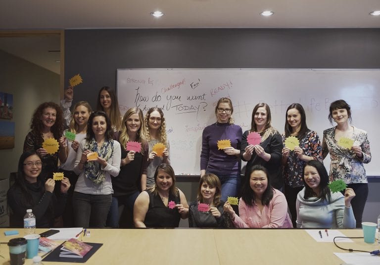 Image of a group of women holding up cards with empowering words during a self care workshop by Vancouver workshop and retreat photographer Angela McConnell