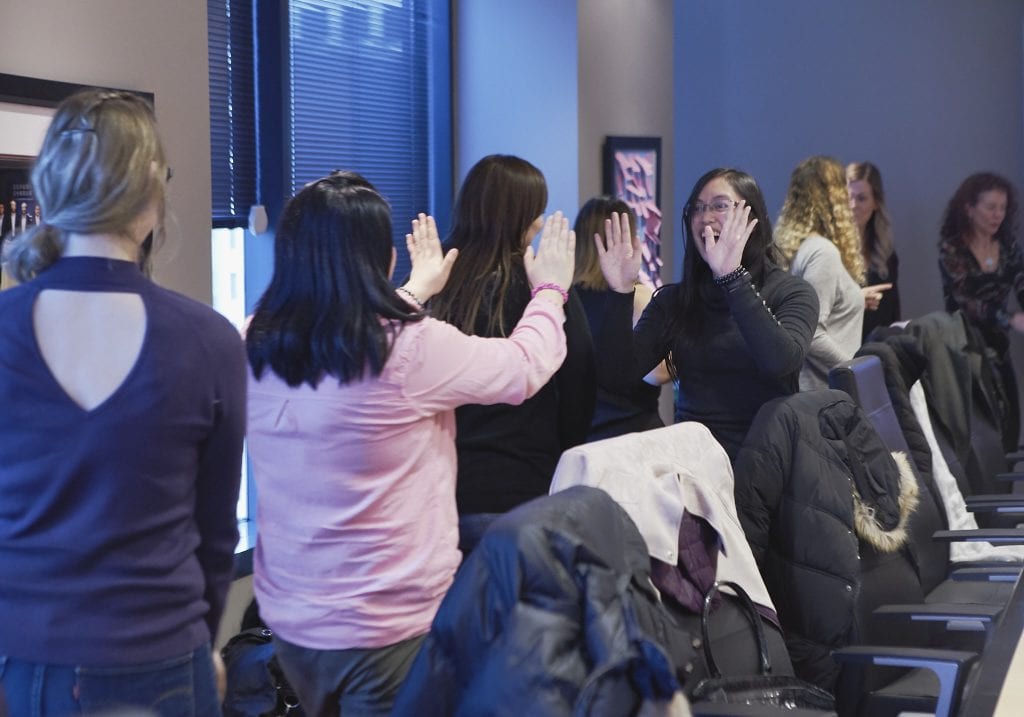 Image of women give each other a high five and laughing during a self care workshop by Vancouver workshop and retreat photographer Angela McConnell