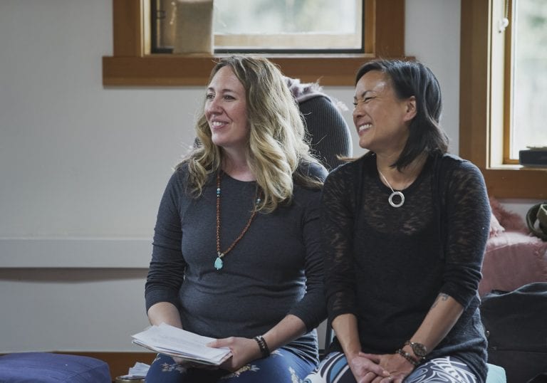 A workshop facilitator and yoga instructor smile at attendees during an introduction at a self care for educators workshop at Roundhouse Farm, Victoria BC by Vancouver workshop and retreat photographer Angela McConnell