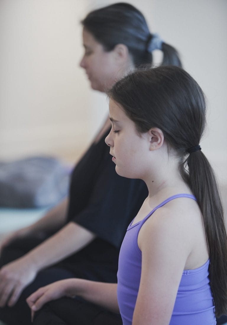 Image of a young girl seated in meditation next to her mother during a mother and daughter workshop by Vancouver workshop and retreat photographer Angela McConnell