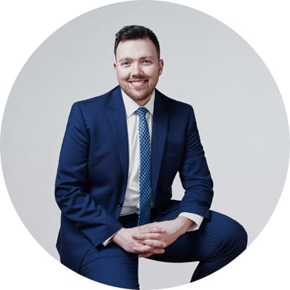 A man in a blue suit sits with his hands clasped and smiles at the camera by Vancouver business portrait and branding photographer Angela McConnell